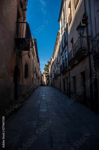 Calle estrecha antigua empedrada con casas y balcones en Salamanca