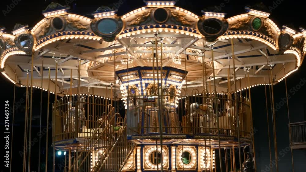 Illuminated merry go round in park. Brightly illuminated roundabout spinning in wonderful amusement park at night.
