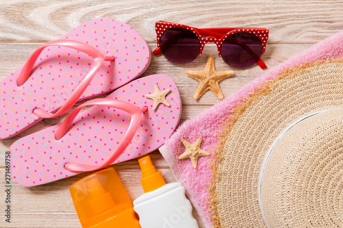 flip flops, straw hat, starfish, sunscreen bottle, body lotion spray on wooden background top view . flat lay summer beach sea accessories background, travel concept