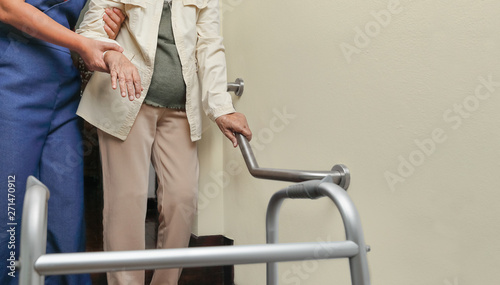 Elderly woman holding on handrail with caregiver
