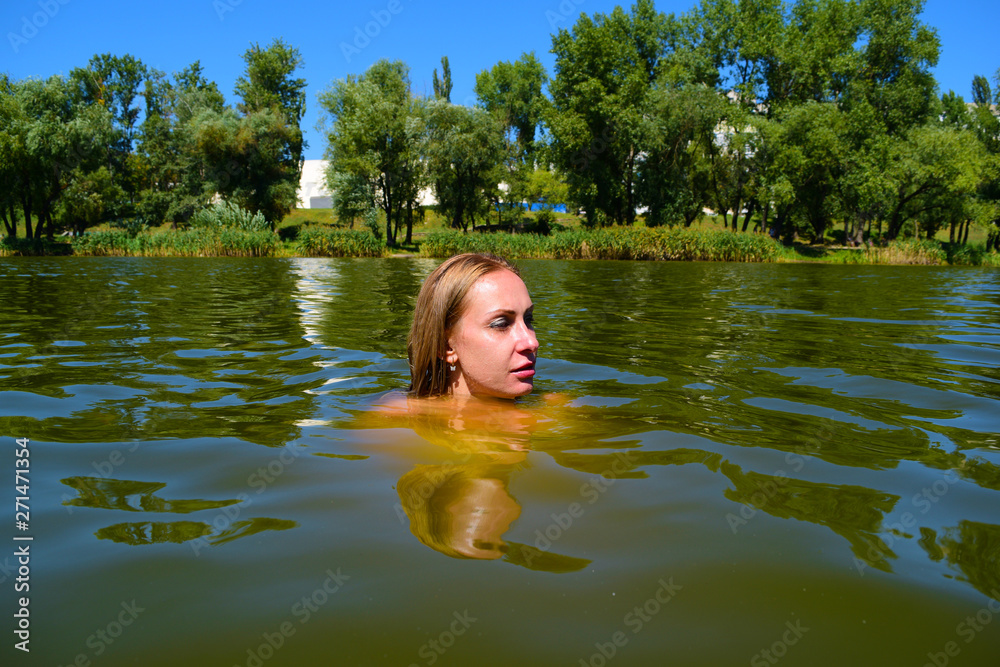 Fototapeta premium Young woman completely in the water on the lake