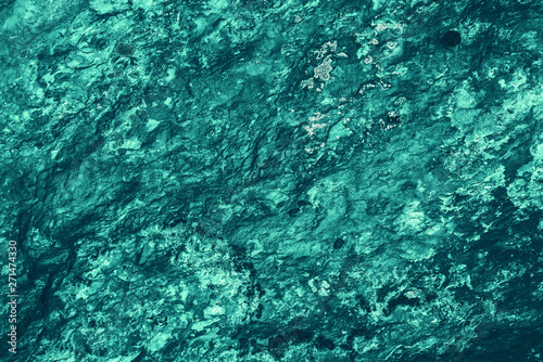 Vintage azure background. Rough painted wall of turquoise color. Imperfect plane of cyan colored. Uneven old decorative toned backdrop of aqzure tint. Texture of teal hue. Ornamental stony surface.