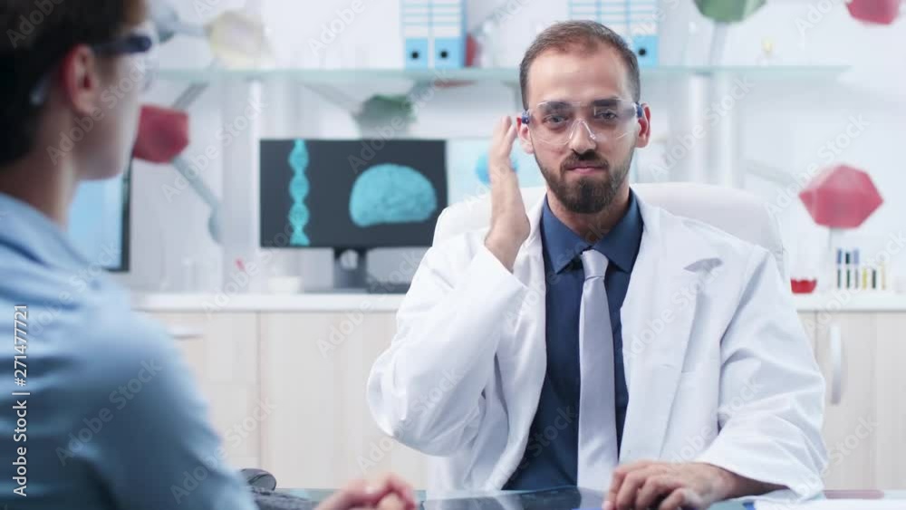 Caucasian physician with AR goggles showing something to a patient in front of him Caucasian physician with AR goggles showing something to a patient in front of him