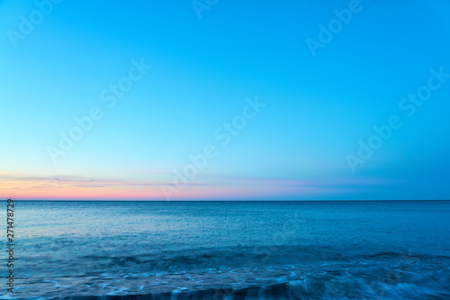                           Waving sea water on a sunset against a blue sky. Copy space.       © Arthur