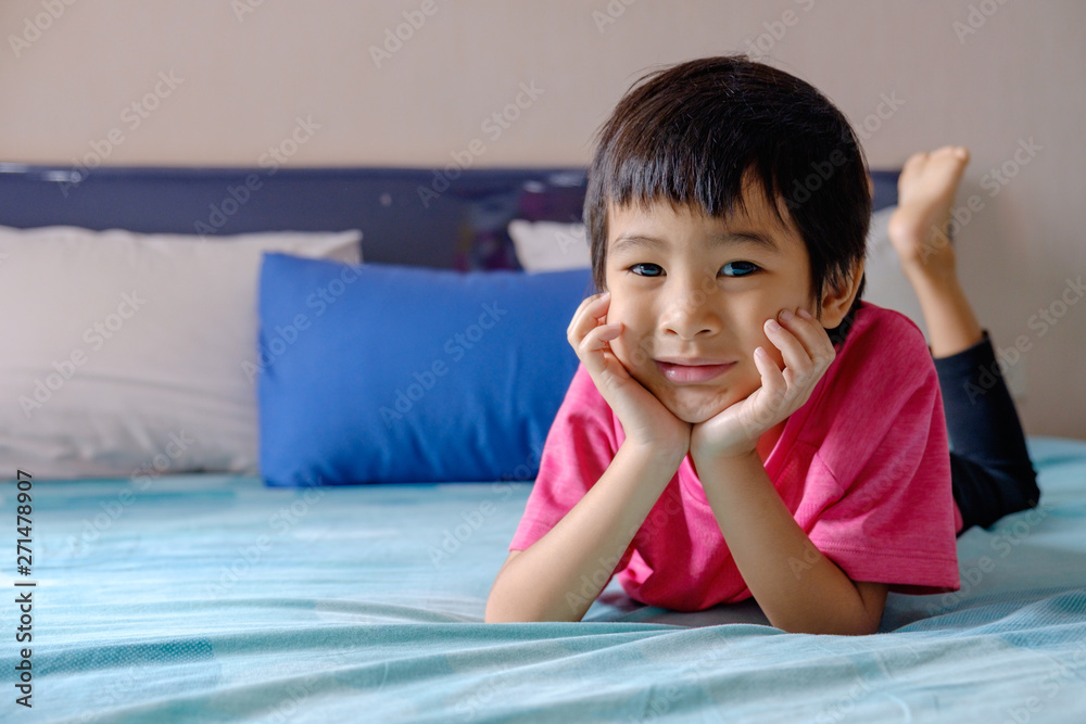 Happy asian boy hand to cheek on blue bed background Happy asian boy hand to cheek on blue bed background