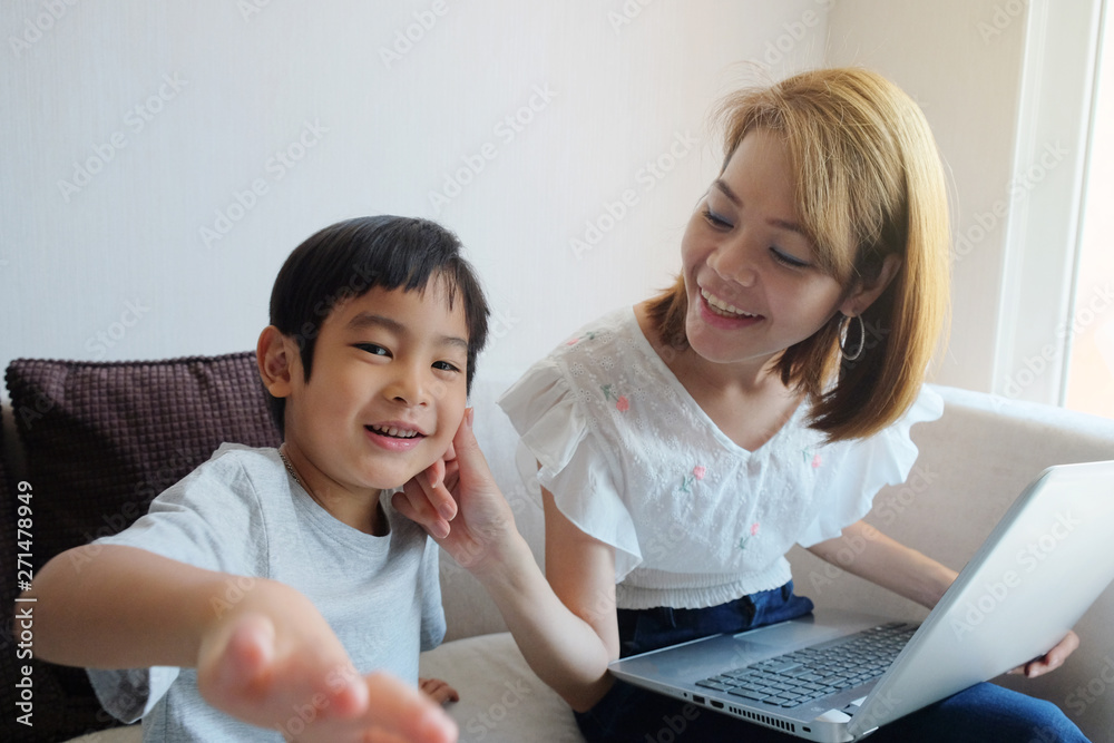 Asian Mother teaching her son for use laptop computer