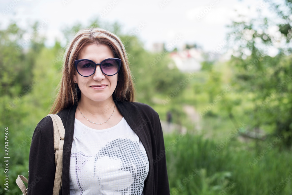 A middle-aged woman in sunglasses returns from work and smiles, she is happy because she will soon see her children and husband A middle-aged woman in sunglasses returns from work and smiles, she is happy because she will soon see her children and husband