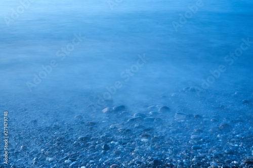 Pebble in water on the beach. Natural background. Copy space.