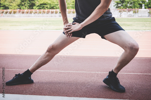 Young fitness athlete man running on road track  exercise workout wellness and runner stretching legs before run concept