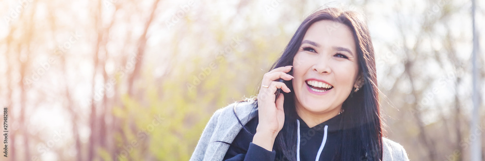 Beautiful young happy Asian girl emotional woman talking on a smartphone in the park Beautiful young happy Asian girl emotional woman talking on a smartphone in the park