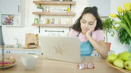 Beautiful african american woman searching for pecipe using notebook at the kitchen photo