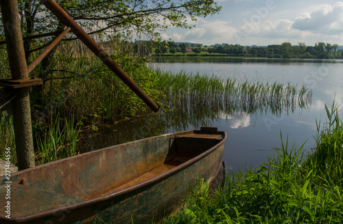 Landscape with an old boat, pond and meadows