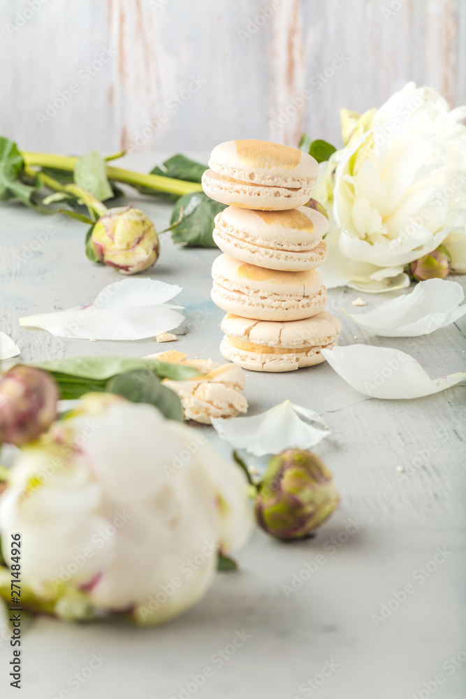 macarons and white peony flowers on wooden surface macarons and white peony flowers on wooden surface
