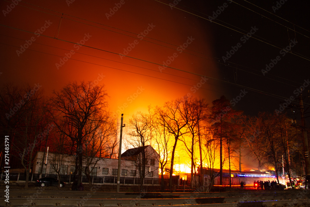 Fire in factory building at night. Firefighters try to put out the fire