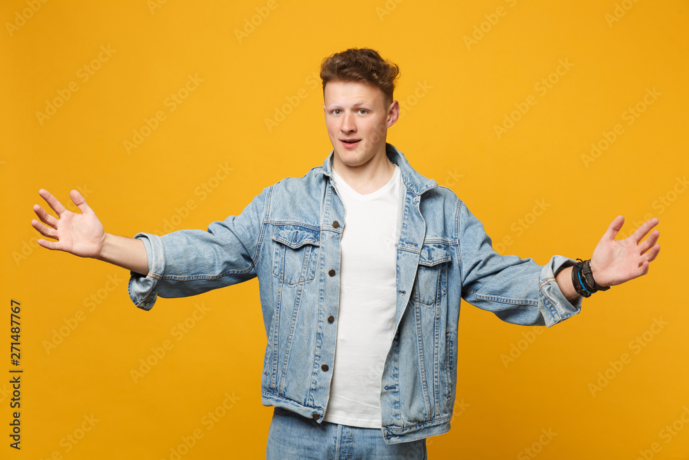 Handsome young man in denim casual clothes gesturing demonstrating size with horizontal workspace isolated on yellow orange background. People sincere emotions, lifestyle concept. Mock up copy space. Handsome young man in denim casual clothes gesturing demonstrating size with horizontal workspace isolated on yellow orange background. People sincere emotions, lifestyle concept. Mock up copy space.