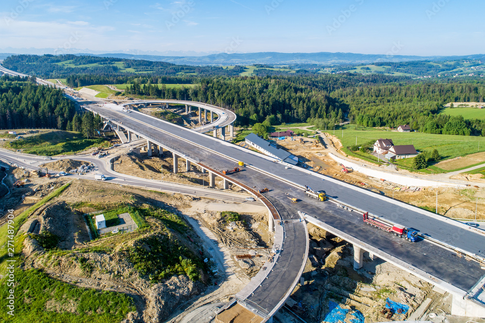 New highway under construction in Poland on national road no 7, E77, called Zakopianka.  Overpass crossroad with traffic circles and viaducts near Naprawa village. Aerial view in June 2019 - obrazy, fototapety, plakaty 