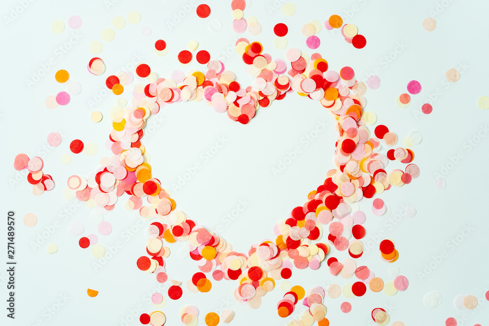 Heart shaped colorful confetti on pastel background