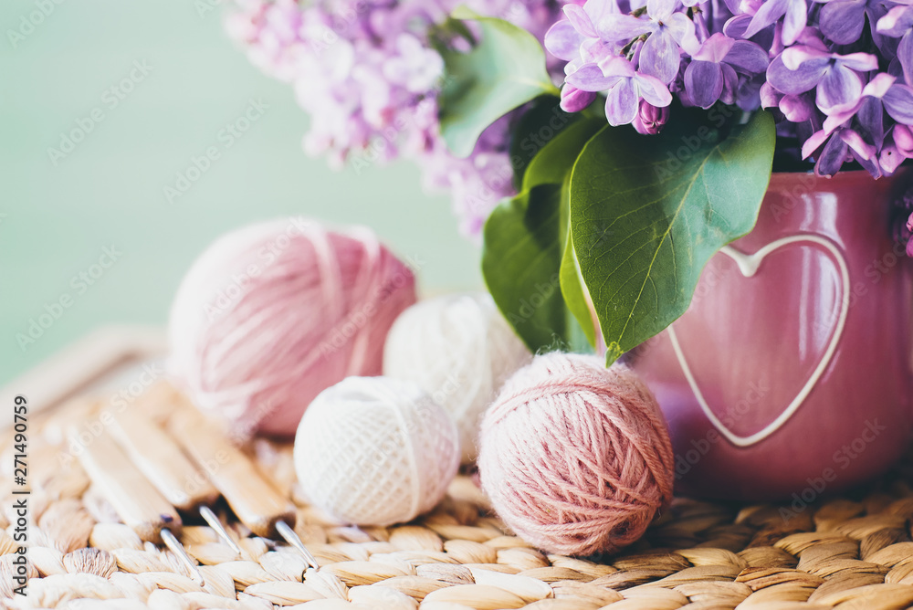 Crochet and knitting. Women's working space. Bouquet of lilac, yarn, crochet hooks on the table. Favorite hobby. Crochet and knitting. Women's working space. Bouquet of lilac, yarn, crochet hooks on the table. Favorite hobby.