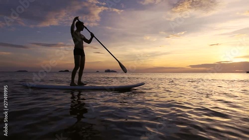 silhouette of man on SUP paddle standing board at sunset, beach leisure activity video