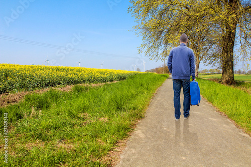 junger Mann trägt seinen Koffer auf einem Weg