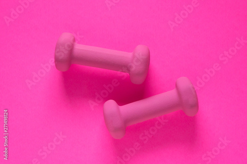 Fitness equipment with womens pink weights/ dumbbells isolated on a pink background with copyspace