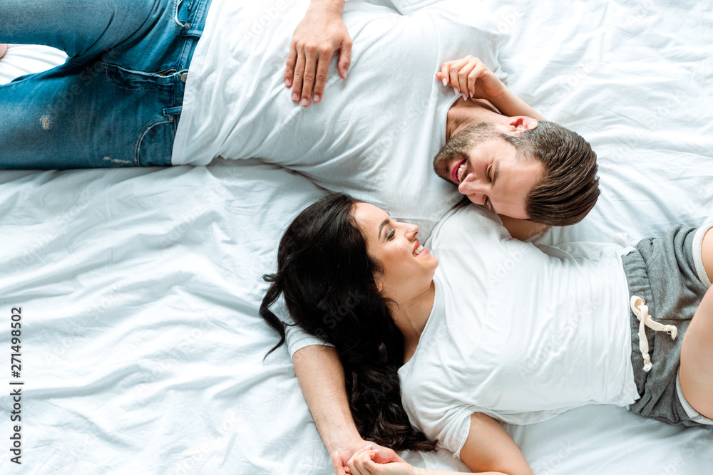 top view of happy couple lying together in bed and looking at each other top view of happy couple lying together in bed and looking at each other