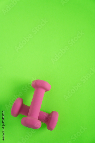 Fitness equipment with womens pink weights/ dumbbells isolated on a lime green background with copyspace