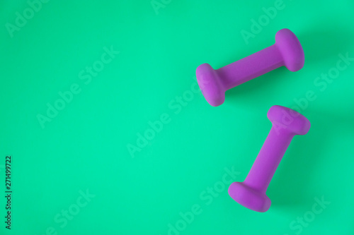 Fitness equipment with womens purple weights/ dumbbells isolated on a teal green background with copyspace