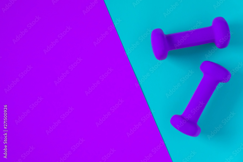 Fitness equipment with womens purple weights/ dumbbells isolated on a light sky blue and purple background with copyspace Fitness equipment with womens purple weights/ dumbbells isolated on a light sky blue and purple background with copyspace