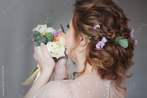 Beautiful and elegant wedding hairstyle. Young bride with bouquet of flowers