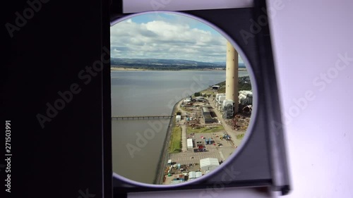 A disk ejecting from a DVD player with overlay of low-level aerial footage over Longannet Power Station. Now disused and in the process of being demolished. photo