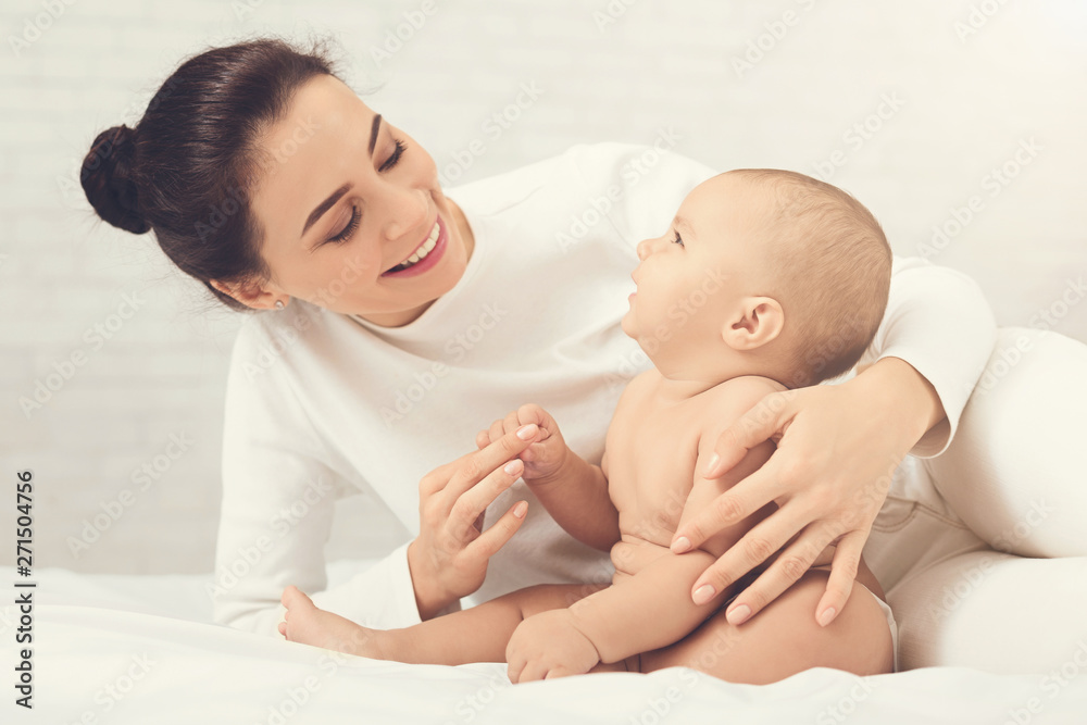 Mother playing with her baby in bedroom. Mother playing with her baby in bedroom.