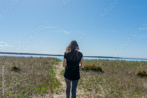 a woman on a defined path walks towards a body of water