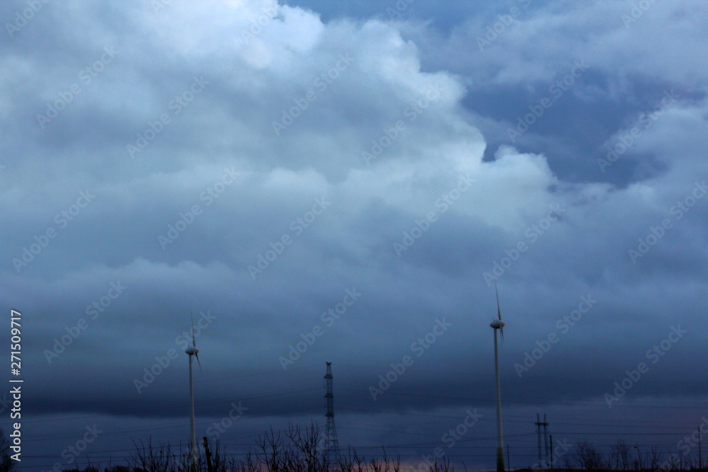 silhouettes of windmill and epic stormy sky on the background