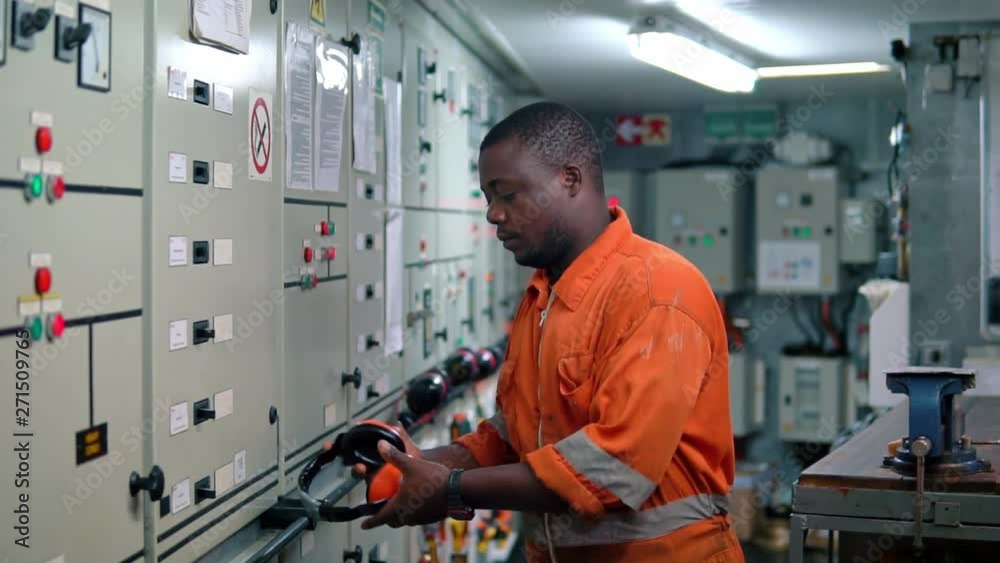 African marine engineer officer in engine control room ECR.