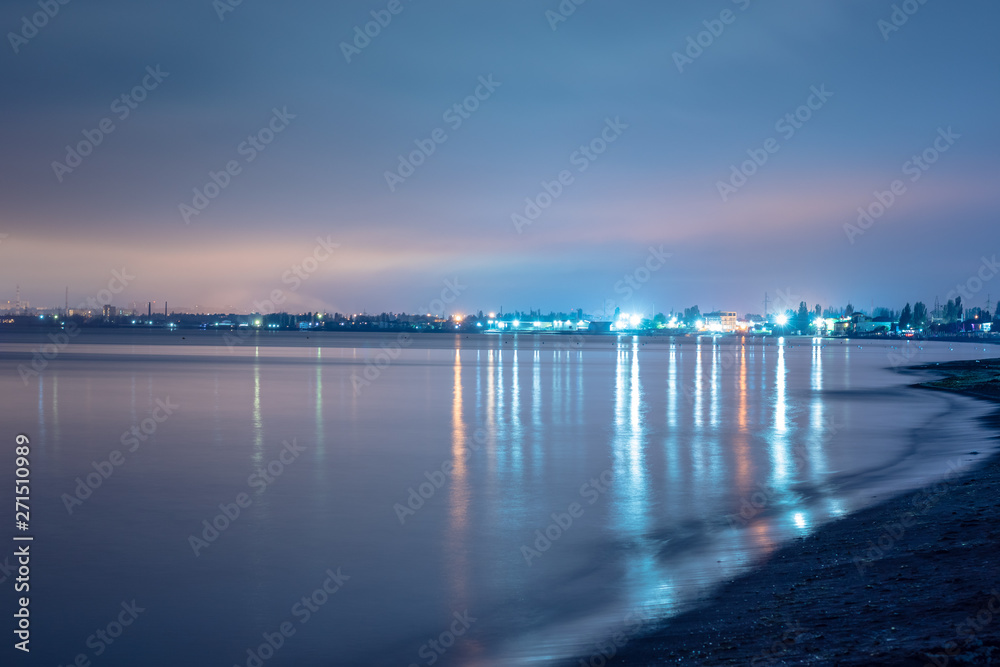 night city lights in the reflection on the beach