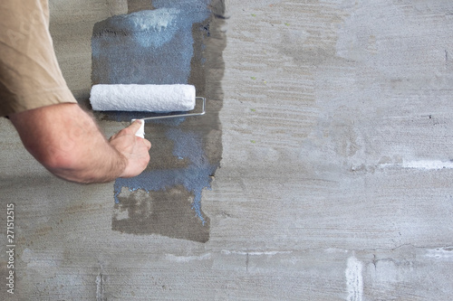 Construction work, plastering and wall priming. Builder's hand with paint roller. Copy space