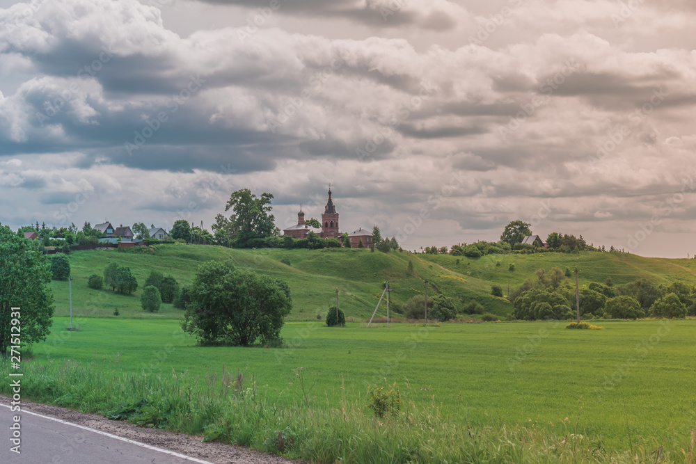 Colorful Bright Sunny Landscape with Russian country-house on hill in a middle of photo with a Bright Contrast cloudy Sky