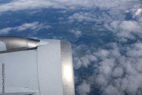 In-flight view on aircraft engine above dark ground and white clouds