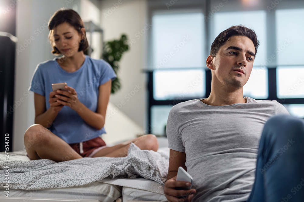 Young couple with cell phones ignoring each other in the bedroom. Young couple with cell phones ignoring each other in the bedroom.