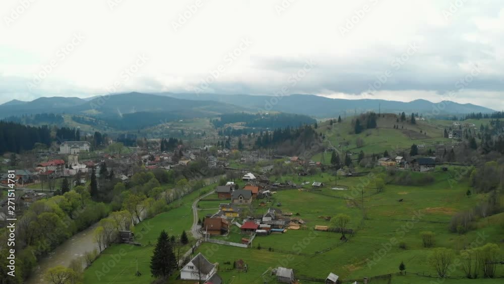 Beautiful mountain landscape with coniferous forest, at the foot of the mountain a small village with wooden houses. Top view Beautiful mountain landscape with coniferous forest, at the foot of the mountain a small village with wooden houses. Top view