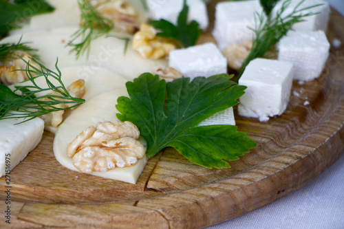 Extreme close-up of different types of cheeses, nuts, herbs and honey on a wooden board, the concept of a healthy snack