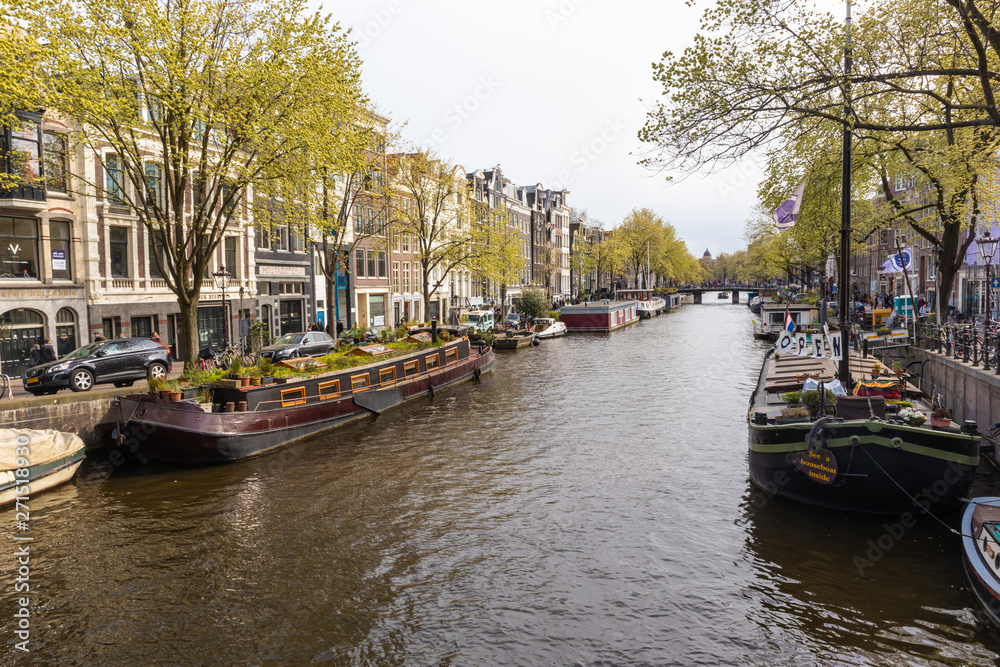 AMSTERDAM, NETHERLANDS - APRIL 13, 2019: Houses and Boats on Amsterdam Canal