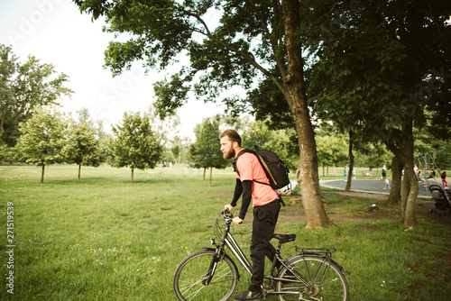 A young and handsome man riding a bicycle in the park