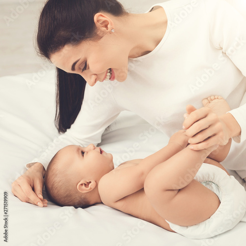 Mother playing with her baby in bedroom.