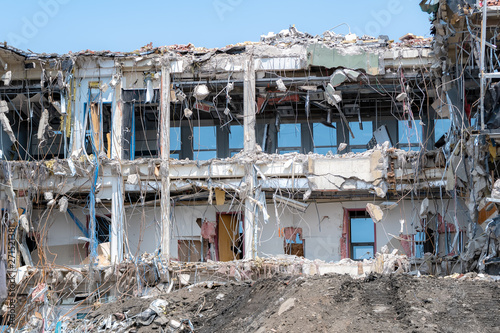 A building in the process of being demolished. Lots of debris and wires. Closeup view on a bright sunny day.