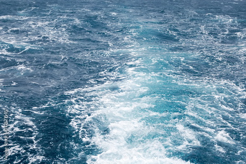 Water wake of cruise liner blue sea splash background.
