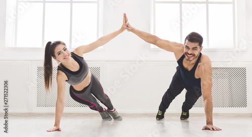 Active couple standing in plank and giving high five with one ha
