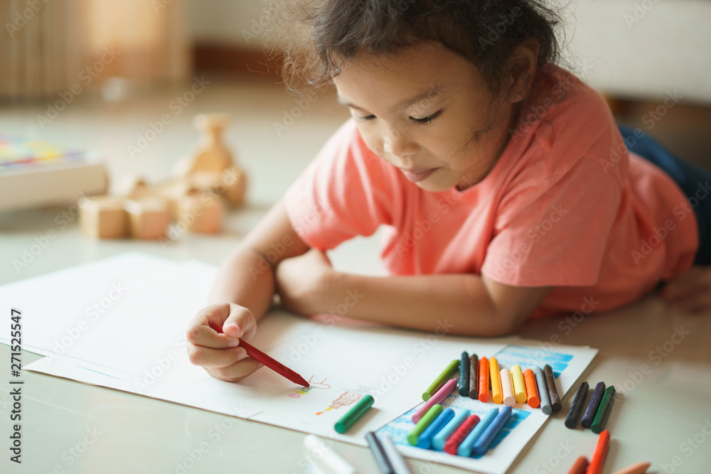 Cute little asian girl drawing homework and writing with color Wax crayons on paper in her home Cute little asian girl drawing homework and writing with color Wax crayons on paper in her home