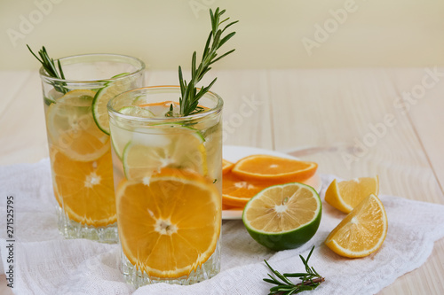 Two glasses of cool refreshing drink with ice  orange and rosemary on a white napkin
